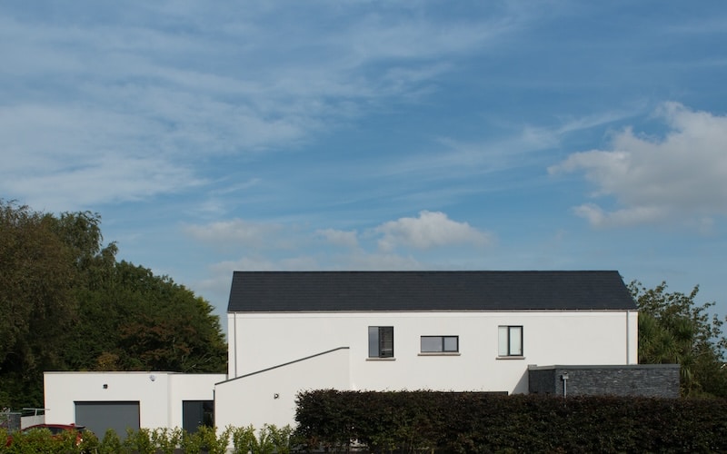 long elevation of new build Greenisland home in white render and slate